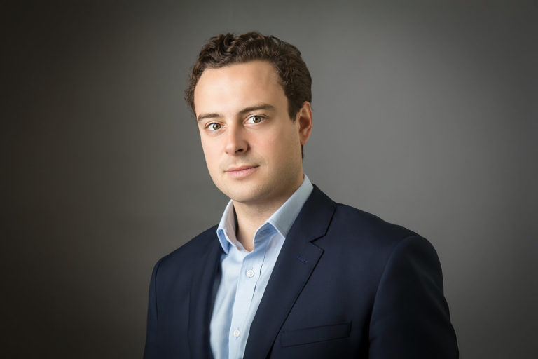 A man wearing a suit and tie smiling and looking at the camera