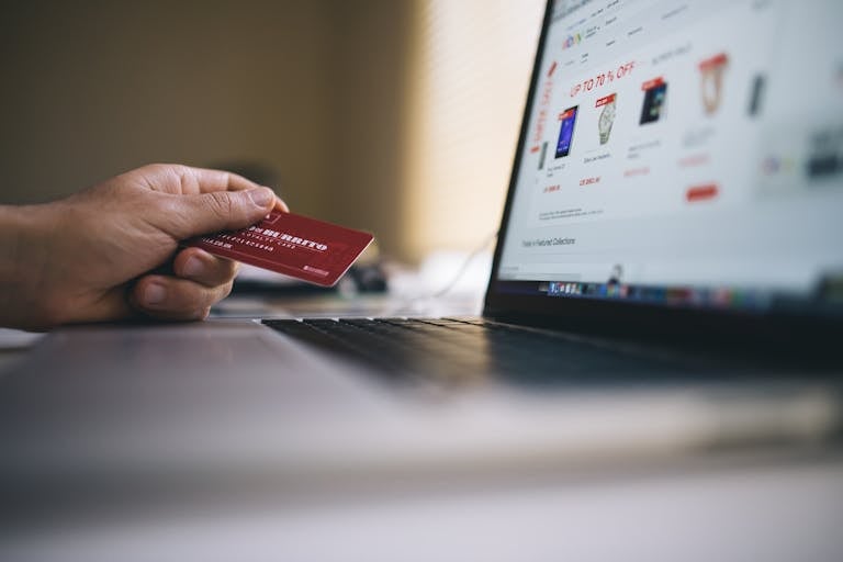 Black and Gray Laptop Computer With Turned-on Screen Beside Person Holding Red Smart Card in Selective-focus Photography