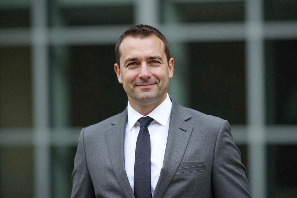 A man wearing a suit and tie smiling at the camera