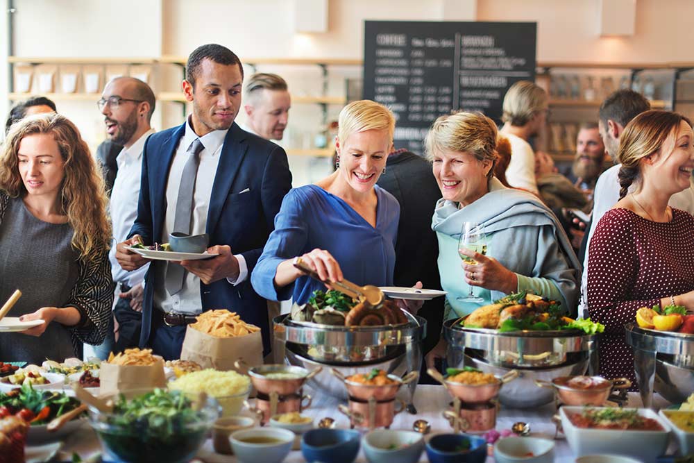 A group of people standing around a table full of food