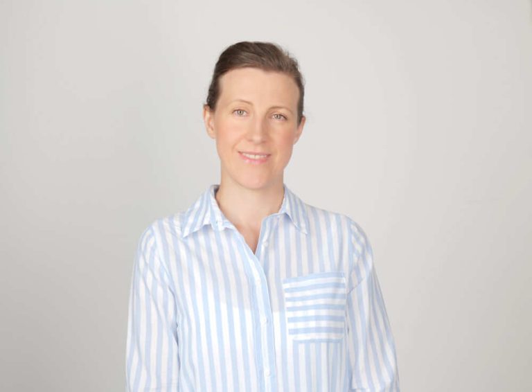 A person wearing a striped shirt and smiling at the camera