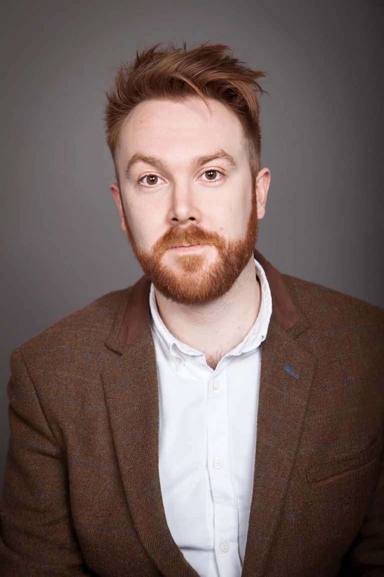 A man wearing a suit and tie smiling and looking at the camera