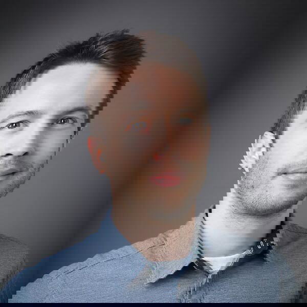 A man wearing a suit and tie smiling and looking at the camera