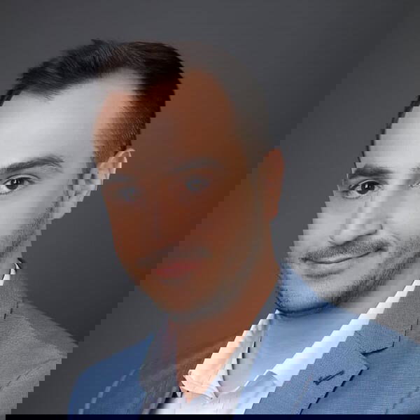 A man wearing a suit and tie smiling and looking at the camera