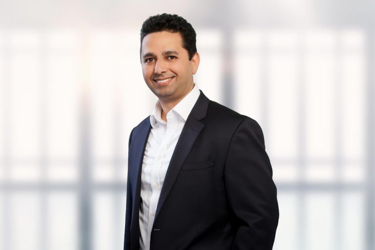 A man wearing a suit and tie standing in front of a window
