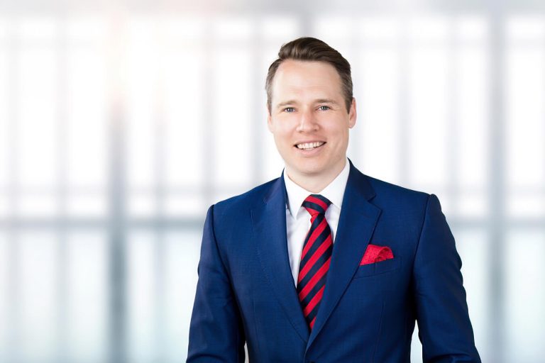 A man wearing a suit and tie smiling at the camera