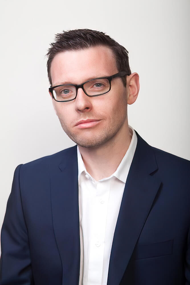 A man wearing a suit and glasses looking at the camera